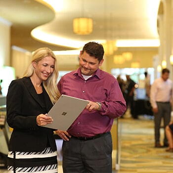 Two AADOM members checking a tablet while smiling