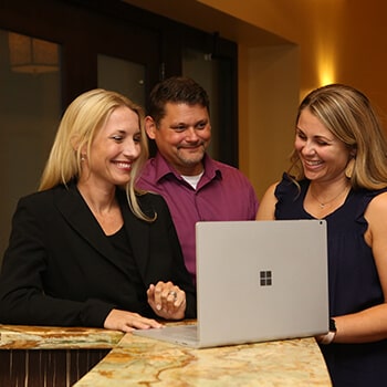 Three AADOM members at a computer smiling